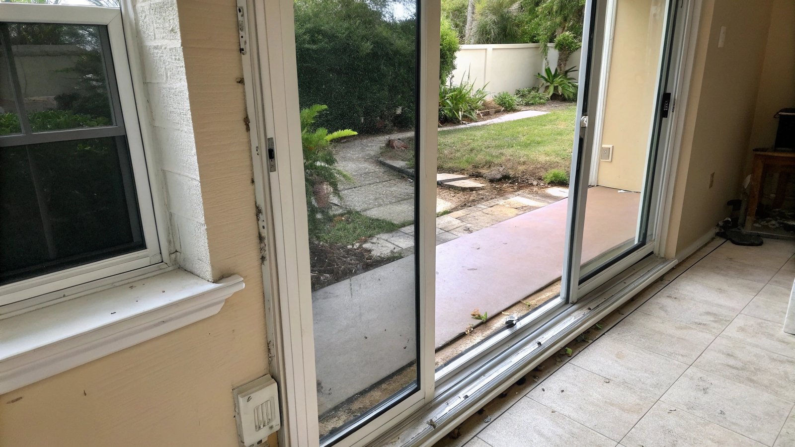 A close-up of a new sliding glass door track installed on a floor.