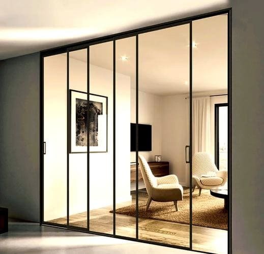 A modern living room with an invisible sliding door track, showing a seamless transition between rooms.