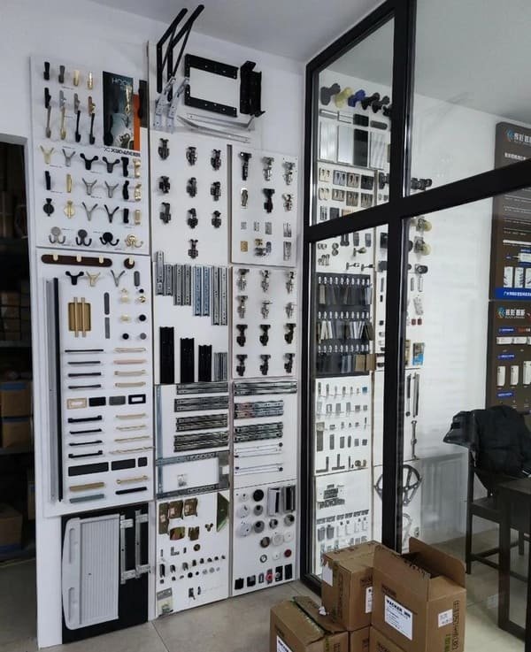 A display board showing different types of furniture hardware like various hinges, drawer slides, and pulls.