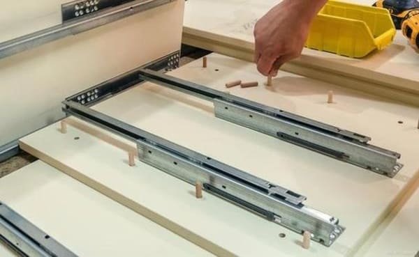 A jig being used to position a drawer slide perfectly inside a frameless cabinet box.