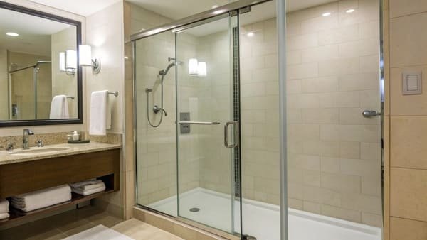 A pristine hotel shower with a clean glass door