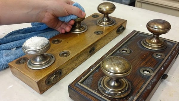 A before-and-after shot of a tarnished brass handle, half of it cleaned and polished to a bright shine.